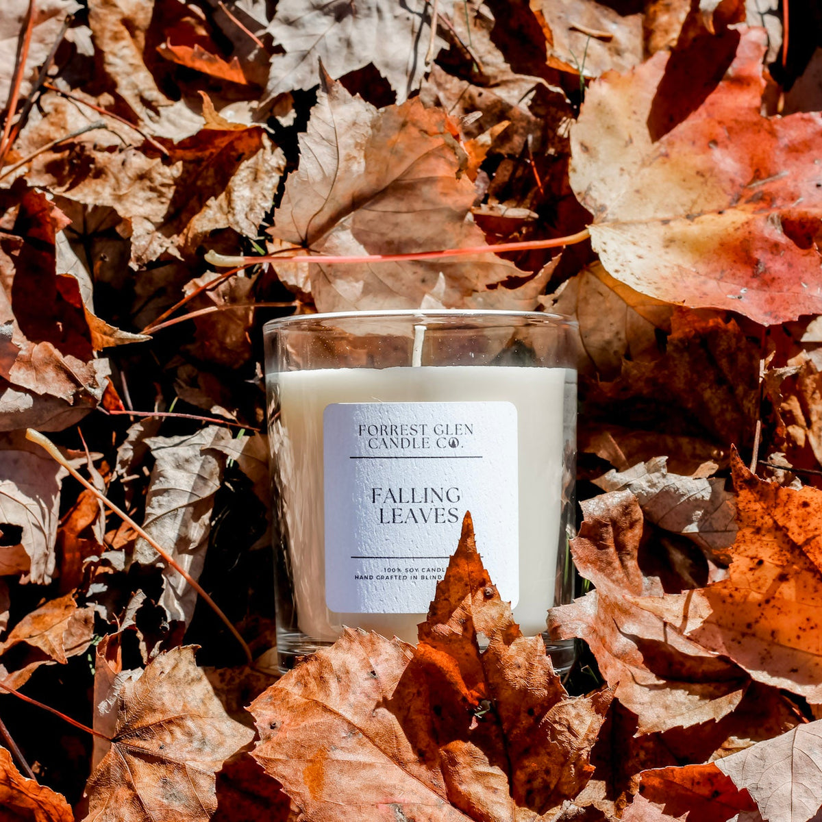 Candle labeled 'Falling Leaves' surrounded by autumn leaves