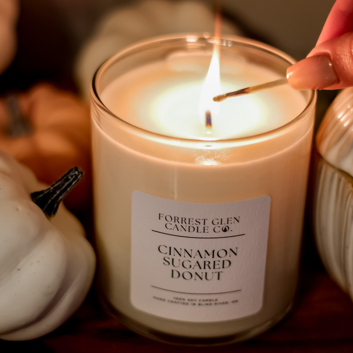 close up of soy wax candle being lit with a match in the fragrance cinnamon sugared donut 