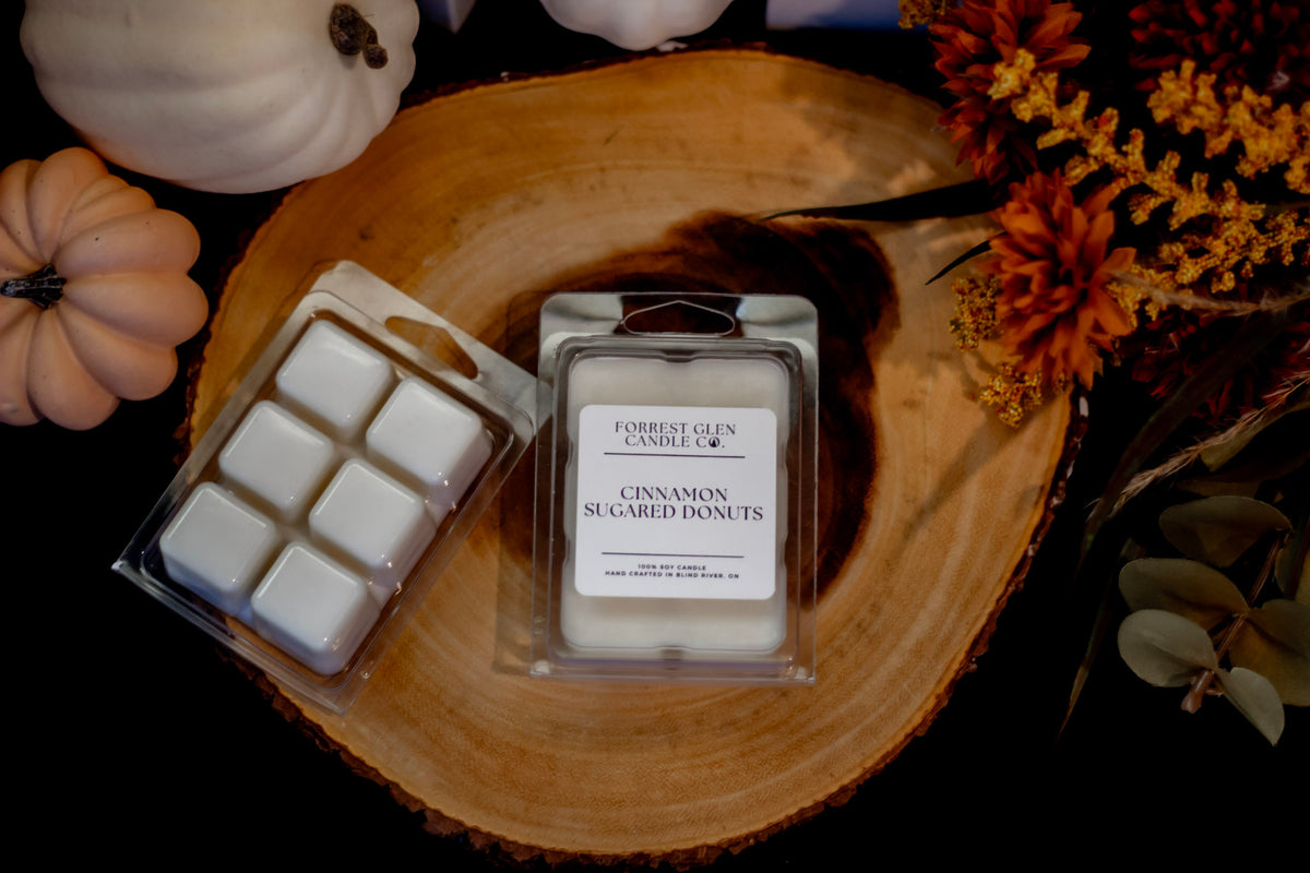 Two Cinnamon Sugared Donut wax melts products from Forrest Glen Candle Co. are displayed on a rustic wood slice.