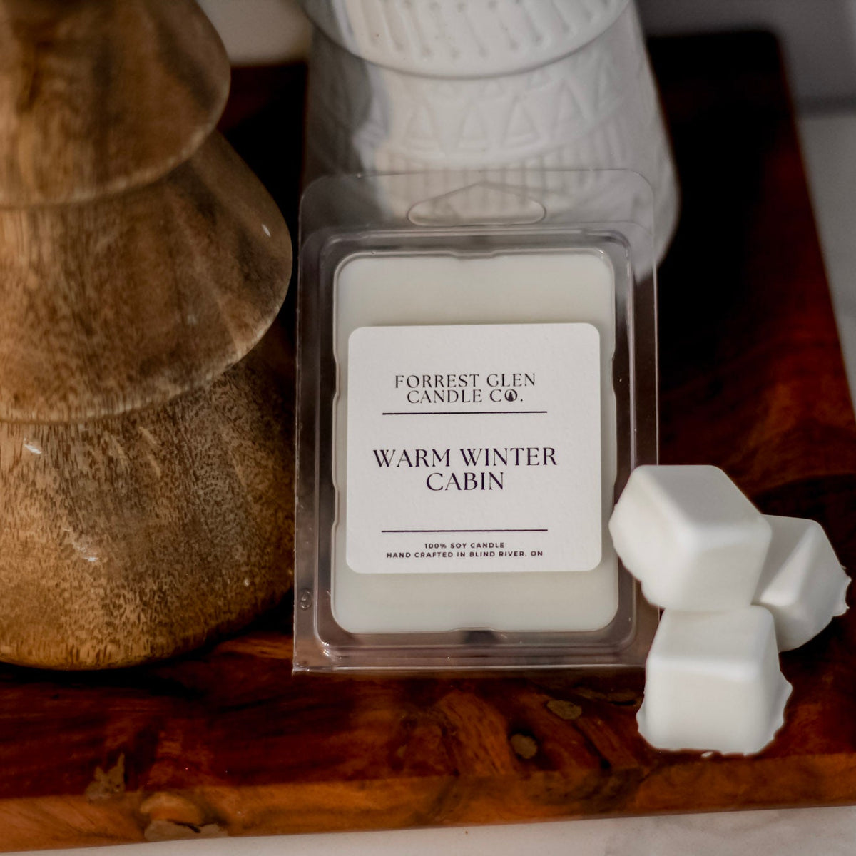 Forrest Glen Candle Co. wax melts on a wooden surface with a decorative Christmas tree.