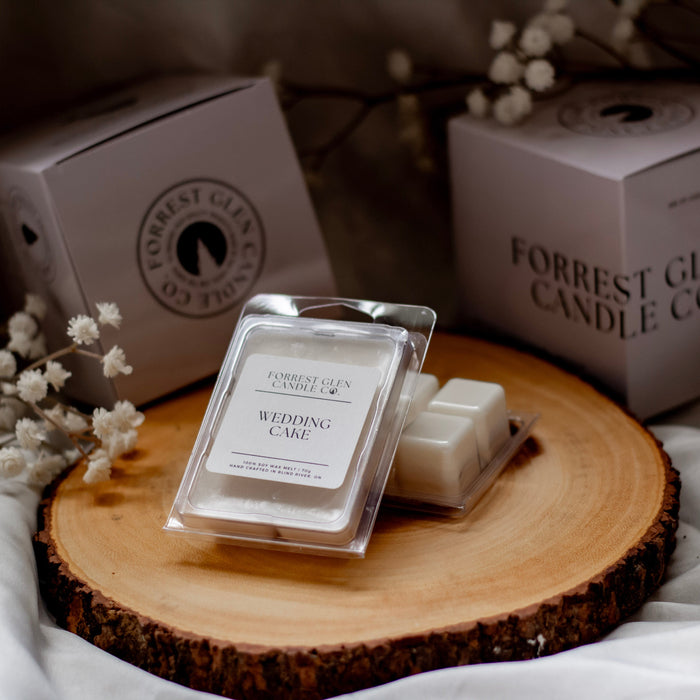 Forrest Glen Candle Co. wax melts on a wooden board with branded boxes in the background.