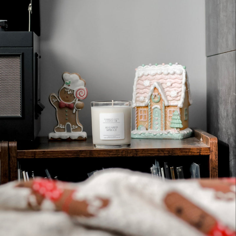 Decorative items including a gingerbread house, candy cane, and candle on a shelf with a blurred foreground.