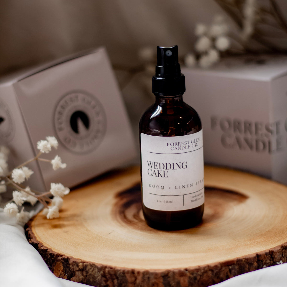 Bottle of 'Wedding Cake' room and linen on a wooden surface with blurred background